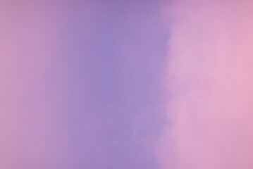 Soft pink purple cloud illuminated by golden light over blue sky background in twilight time. Empty natural sky with pastel tone colors for background or wallpaper.
