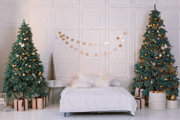 Two big Christmas trees and a garland above the bed