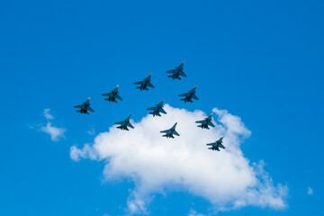Nine combat military aircraft in the sky against a white cloud background