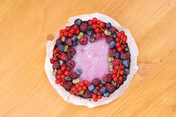 Festive cake, blueberry and blackberry sponge cake with cream cheese inside on a plate on a wooden table, horizontal view from above.