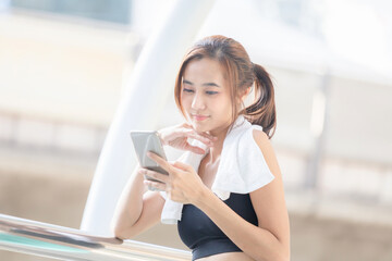 Portrait of Asian girl in fashion sportswear with smartphone at stadium outdoors, Sports blog and outdoor workout.