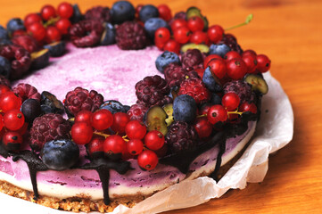 Festive cake, blueberry and blackberry sponge cake with cream cheese inside on a plate on a wooden table, horizontal view from above.