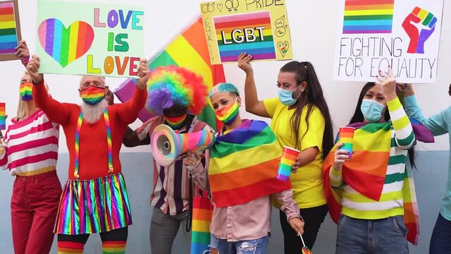 Happy multiracial people dance at gay pride parade with banner and lgbt rainbow flag - Slow motion 