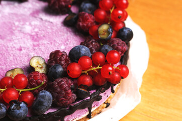 Festive cake, blueberry and blackberry sponge cake with cream cheese inside on a plate on a wooden table, horizontal view from above.Macro photo.