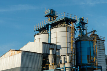 silver silos on agro manufacturing plant for processing drying cleaning and storage of agricultural products, flour, cereals and grain. Large iron barrels of grain. Granary elevator