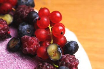Festive cake, blueberry and blackberry sponge cake with cream cheese inside on a plate on a wooden table, horizontal view from above.Macro photo.