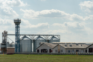 silver silos on agro manufacturing plant for processing drying cleaning and storage of agricultural products, flour, cereals and grain. Large iron barrels of grain. Granary elevator