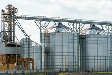 Obraz premium silver silos on agro manufacturing plant for processing drying cleaning and storage of agricultural products, flour, cereals and grain. Large iron barrels of grain. Granary elevator