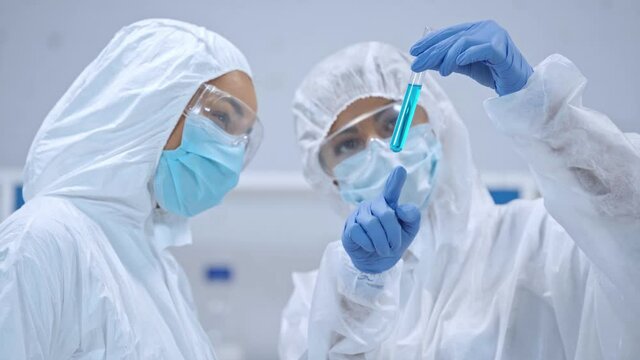 African american scientist holding test tube and talking with colleague