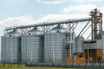 Obraz premium silver silos on agro manufacturing plant for processing drying cleaning and storage of agricultural products, flour, cereals and grain. Large iron barrels of grain. Granary elevator
