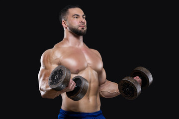 Young muscular sportsman is lifting heavy dumbbells showing his strong biceps isolated on black backgrounds