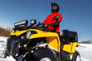 Young man driver on the ATV quad bike stand in heavy snow with deep wheel track. Moto winter sports. © Screaghin