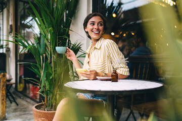 Cheerful woman enjoying coffee in sidewalk cafe