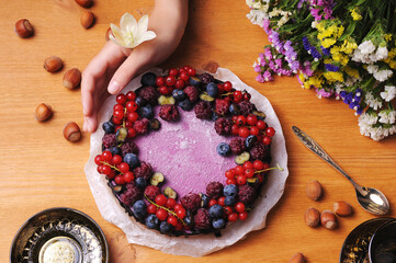 Festive cake, blueberry and blackberry sponge cake with cream cheese inside on a plate on a wooden table, horizontal view from above.