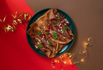 Chocolate pancakes or crepes with cranberries and nuts, served on a green plate. Winter holidays breakfast concept. Breakfast for Christmas and New Year. Brown background 