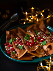 Chocolate pancakes or crepes with cranberries and nuts, served on a green plate. Winter holidays breakfast concept. Breakfast for Christmas and New Year. Dark background 