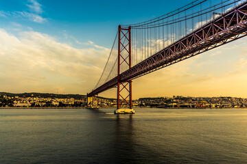 Looking up at the 25th of April bridge in Lisbon, Portugal from the river Tagus in the early morning light at sunrise in Autumn