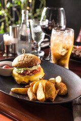 cheeseburger with french fries and glass of cider on the table at restaurant