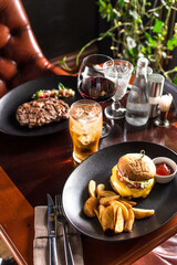 cheeseburger with french fries and glass of cider on the table at restaurant