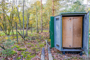 Disused control relay box of the old Iron Rhine railway (IJzeren Rijn), surrounded by autumn trees with yellowish green foliage, Meinweg nature reserve in Middle Limburg, the Netherlands