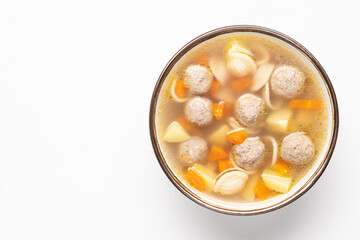Delicious homemade soup with chicken or turkey meatballs. Vegetables and pasta ingredients. White background, top view, copy space