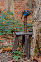 Old and rusty metal post with a base next to a tree trunk in the Meinweg nature reserve, next to what was the old Iron Rhine Railway (IJzeren Rijn), autumn day in Middle Limburg, Netherlands