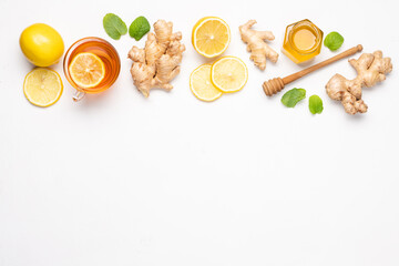Hot tea with ginger, honey and lemon in glass cup. Immune system support with alternative medicine.  White background, Top view, Сopy space