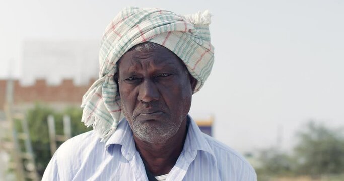 Closeup of an senior man farmer as he struggles to wear a face mask on his terrace in rural area