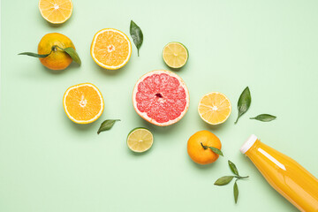 Creative neatly arranged food layout of fruits, vegetables and leaves on pastel green background.  Flat lay juicy citrus fruits and bottle of freshly squeezed juice