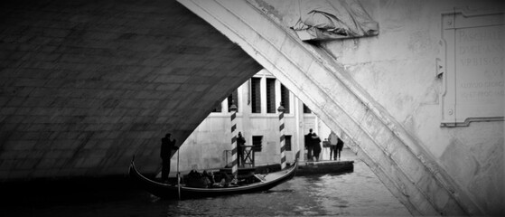 Venice, Italy, December 28, 2018 evocative black and white image of the Rialto Bridge, one of the best known city symbols with passage of gondola