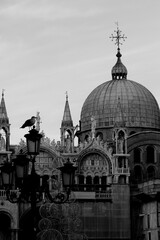 Venice, Italy, December 28, 2018 evocative black and white image of the dome of the Basilica of San Marco on the background with a seagullperched on a lamppost in the foreground