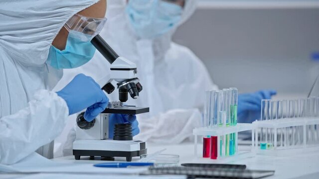 focus pull of african american scientist analyzing sample near coworker