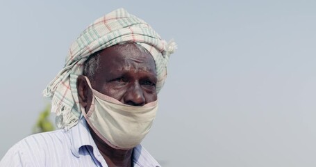Closeup of an senior man farmer wearing a face mask on his terrace in rural area as he adjust it to cover his exposed nose  - Powered by Adobe