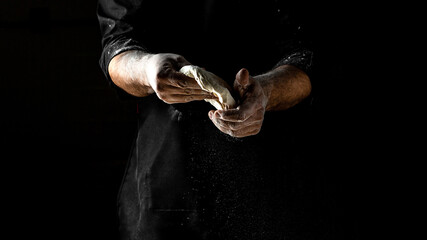 Fototapeta na wymiar Man sprinkling flour over fresh dough for pizza, Cooking bread. Kneading the Dough, men hands with flour splash