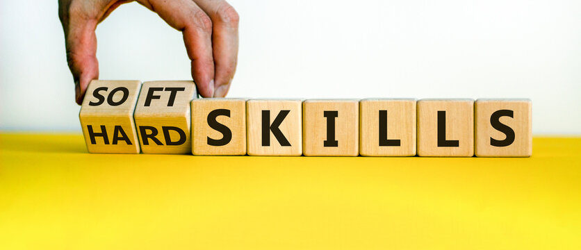 Hard skills versus soft skills. Hand flips cubes and changes the expression 'hard skills' to 'soft skills' or vice versa. Beautiful yellow table, white background. Business concept. Copy space.