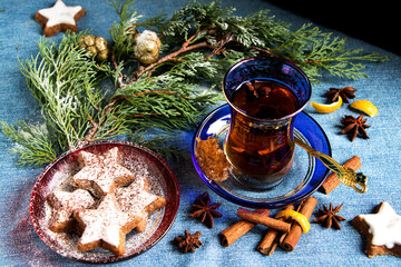 weihnachtliche zimtsterne mit einem glas tee, zimtstangen, sternanis, zitronenschale und einem...