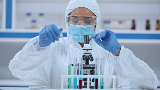 African american scientist analyzing sample in microscope