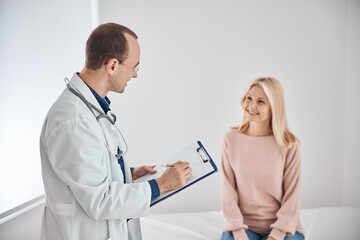 Fototapeta premium Smiling dark-haired physician interviewing the beautiful female patient