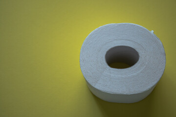 Top-down view of a roll of white toilet paper on a plain yellow background