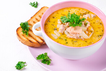 Soup with red fish and cream topped with fresh parsley served in the ceramic tureen
