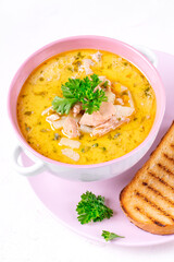 Soup with red fish and cream topped with fresh parsley served in the ceramic tureen