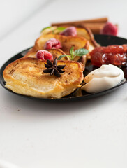Breakfast with pancakes on plates, sour cream and pavidl. Pancakes are on a white table and the guy is holding in his hands.