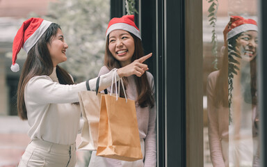 Fototapeta na wymiar Two women doing window shopping and holding bags in christmas season
