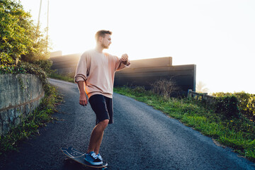 Energetic sportsman with skateboard looking at wristwatch