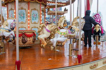 Fototapeta na wymiar Carousel! Horses at the old carnival, people have fun at Christmas!
