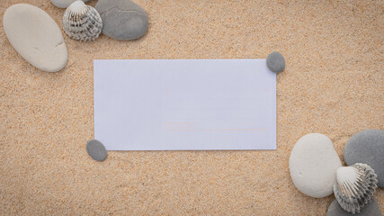 Fototapeta na wymiar Arrière-plan grains de sable de mer, sable fin de plage avec enveloppe et coquillages. Emplacement pour texte sur papier. 