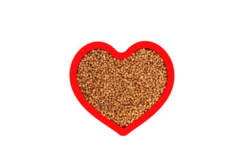 Brown buckwheat groats in heart shape red frame isolated on white.