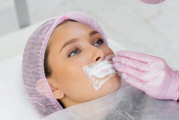 Moisturizing the lips during a cosmetic procedure for a young girl. Cosmetology