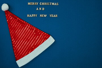 Christmas hat on a blue background and the inscription Merry Christmas and Happy New Year. New Year's decor. Copy space, mock up.