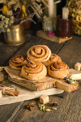 Homemade cinnamon rolls on a wooden board on a dark background, photo of food in a dark style.